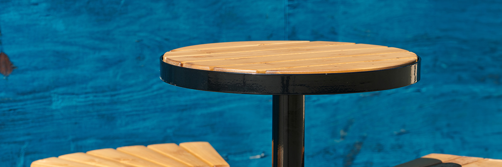 Close up of an outdoor casual seating bark table, it is wooden with black steel frame.